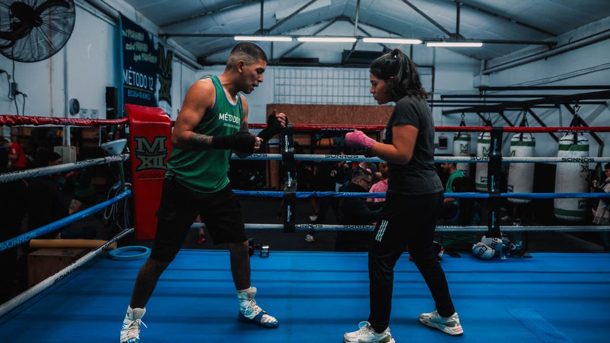Focused boxing training in a Buenos Aires gym with two athletes preparing in the ring.